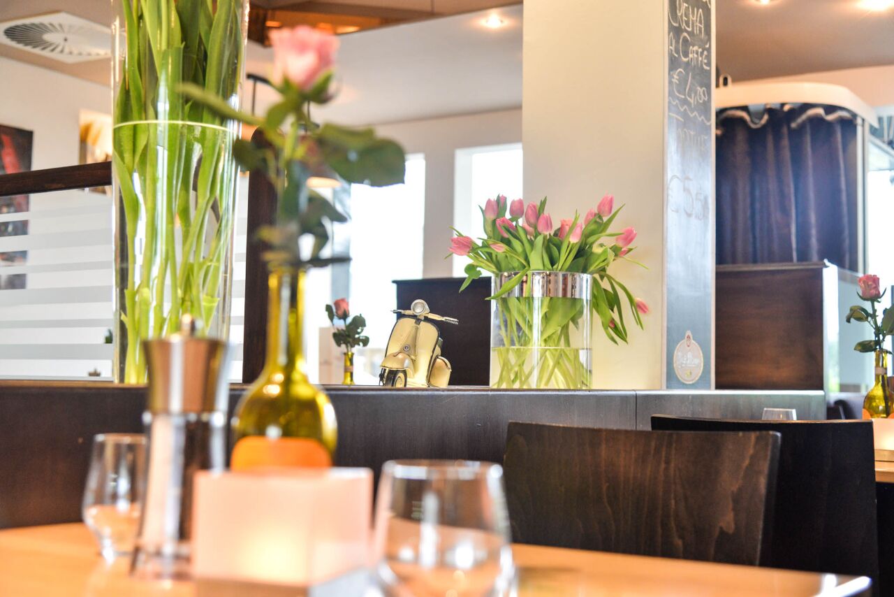 Tulpen und Rosen im Gastraum, im Hintergrund Kreidetafel und Vespa