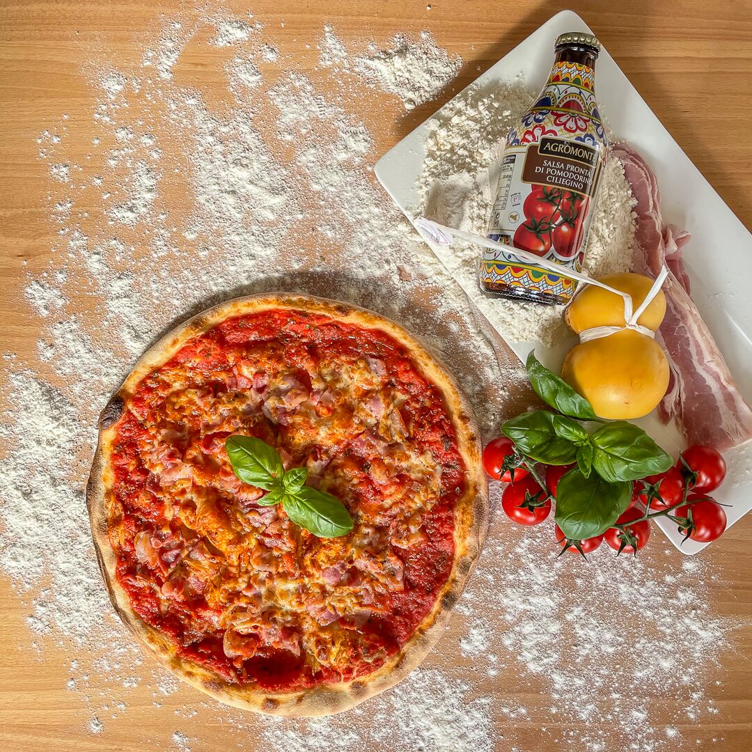 Pizza Abruzzese mit Tomatensauce und Basilikum auf bemehltem Holz